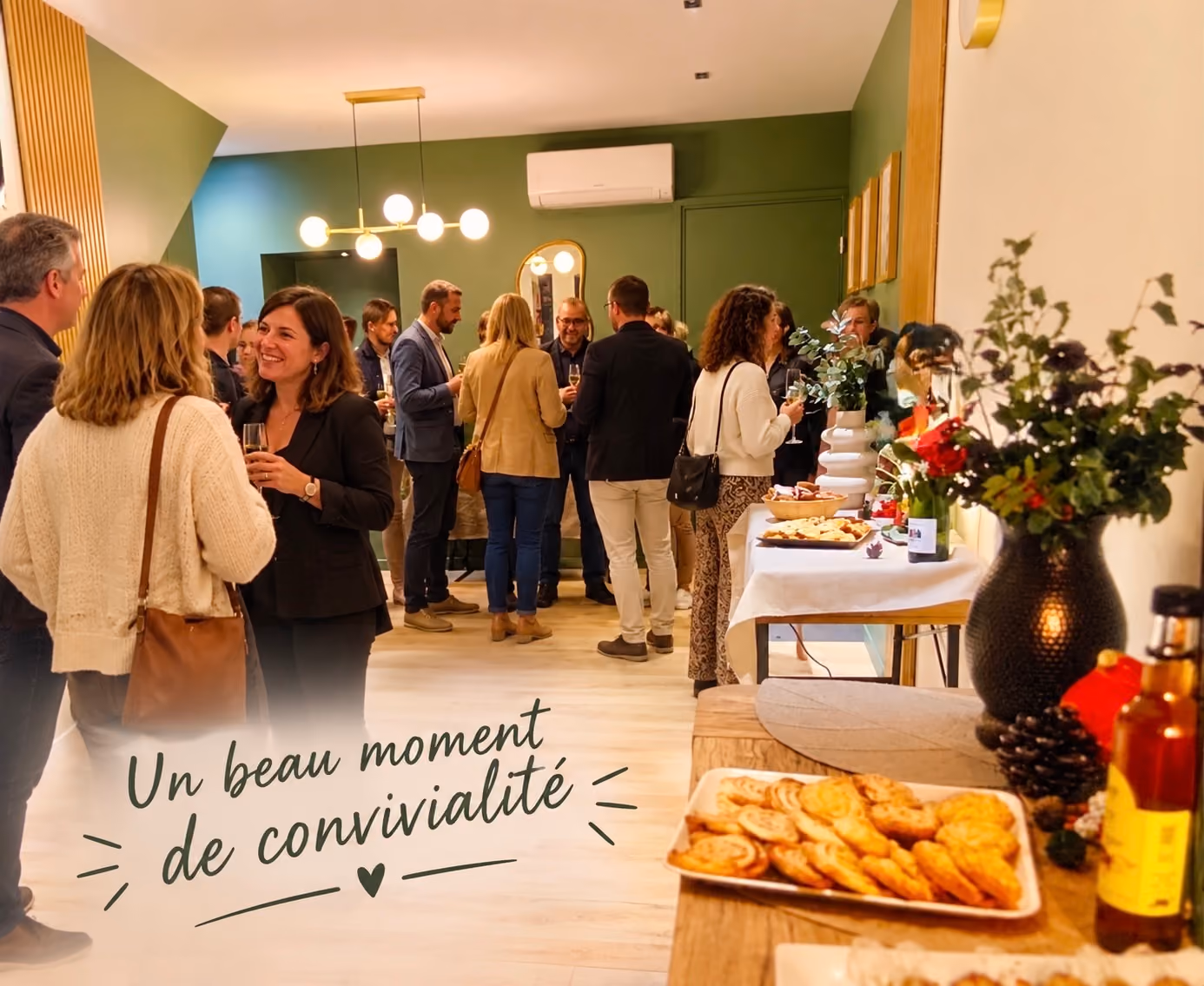 Invités discutant dans l’agence DÉCO.IMMO lors de l’inauguration, devant le buffet et ses compositions végétales